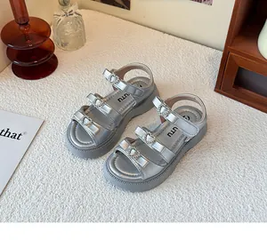 Detalle de sandalias plateadas para niña con hebillas de corazón con strass.
