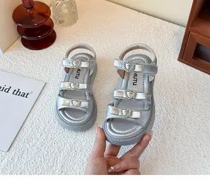 Primer plano de sandalias plateadas para niña con hebillas de corazón con diamantes