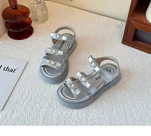 Detalle de sandalias plateadas para niñas con hebillas de corazón de strass y lazos