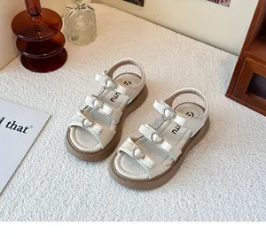 Vista de detalle de sandalias crema para niños con elegantes hebillas de corazones y lazos