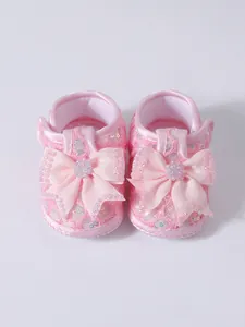 Close-up of pink baby princess shoes with sequin lace and large bow detail