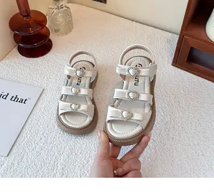 Detalle de las sandalias blancas para niñas con hebillas de corazón brillante y lazos