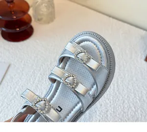 Detalle de sandalias plateadas de niña con hebillas de corazón con brillantes.