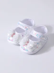 Detail view of white sequined baby shoes with large glittery bow and soft sole