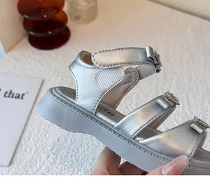 Primer plano de sandalias plateadas para niñas con lazos de diamantes y suela blanda