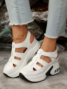 Primer plano de sandalias blancas con plataforma, cuña gruesa y cierres de velcro.