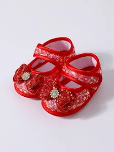Detailed view of red newborn princess shoes featuring glittery bow and rhinestones