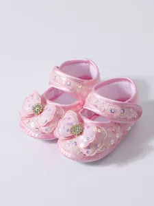 Detailed view of pink sequined baby princess shoes with sparkling bows and soft soles