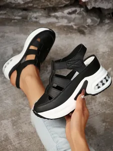 Primer plano de sandalias de cuña con plataforma en blanco y negro con cierre de velcro.