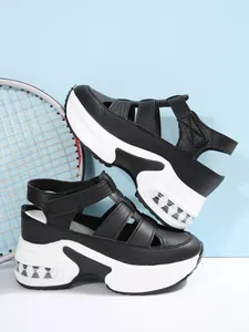 Detalle de sandalias de plataforma negras y blancas con suela de cuña deportiva.