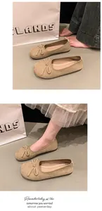 Primo piano di mocassini in camoscio beige con fiocco decorativo e design slip-on comodo.