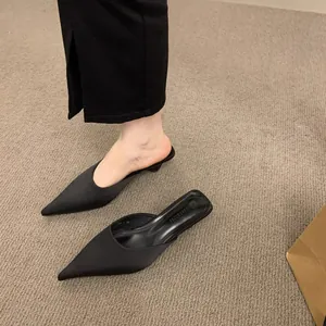 Nahaufnahme der schwarzen spitzen Satin-Mules mit elegantem Pfennigabsatz
