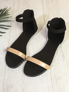 Dettaglio di sandali bassi in stile francese con base nera e cinturino beige in vernice