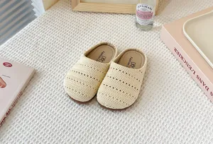 Primer plano de zuecos beige trenzados y transpirables para niñas sobre fondo de tela