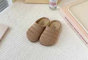 Primer plano de zuecos de punto marrón transpirables para niños sobre una tela con textura