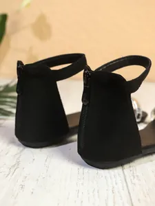 Primo piano del dettaglio della zip posteriore e del cinturino alla caviglia dei sandali neri