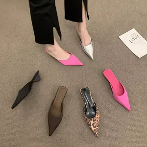 Vielzahl eleganter Mules mit hohem Absatz und spitzer Zehenpartie auf Teppich