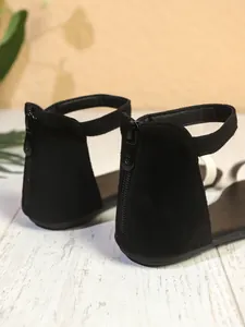 Vista posteriore dettagliata di sandali bassi neri con cerniera e cinturino alla caviglia.