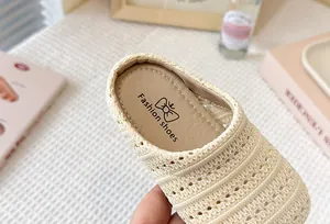 Vista macro de la textura tejida transpirable en mules color crema para niños.