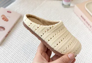 Primer plano de una chinela de punto beige transpirable para niños con un diseño calado