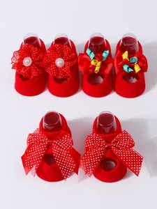 Detailed view of red baby socks featuring decorative bows and flower patterns