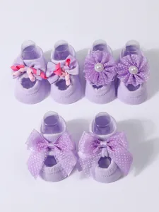 Detailed set of three pairs of purple baby floor socks with bows and flower accents
