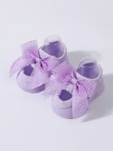 Close-up of cute purple baby floor socks featuring large mesh polka dot bow accents