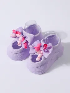 Detail of cute purple baby floor socks featuring a large ribbon bow and anti-slip grip