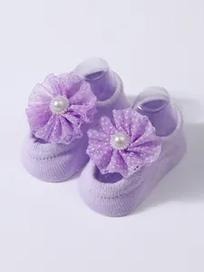 Detailed view of purple baby floor socks with decorative mesh flowers and pearls.