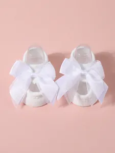 Detail view of white baby socks featuring large and delicate lace bow decorations
