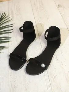Eleganti sandali piatti neri minimalisti con cinturino lucido per un'estate di stile