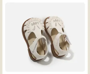 Detalle de lindas sandalias crema para niña con orejas de conejo de encaje y bordado LOVE