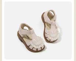 Primer plano de sandalias rosas para niños con encaje y bordado de orejas de conejo.
