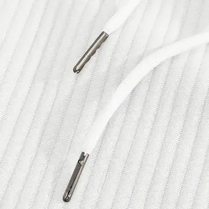 Close-up of white drawstring with metal tips on textured jacquard fabric shorts.