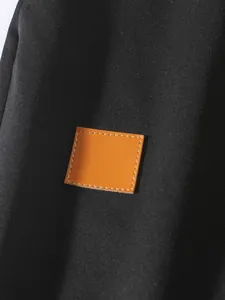 Dettaglio ravvicinato di una toppa in pelle marrone cucita su pantaloncini cargo neri in cotone