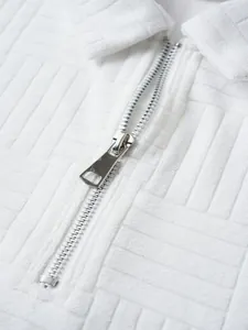 Macro detail of a white textured polo shirt featuring a durable silver metal zipper closure
