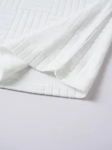 Close-up detail of white men's polo shirt featuring an embossed geometric knit texture