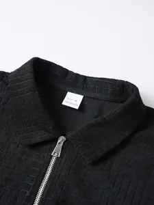 Close-up detail of black textured polo shirt collar with size M tag and metal zipper