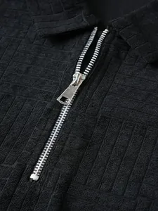 Macro view showing the silver metal zipper and intricate brick-patterned black polo fabric.