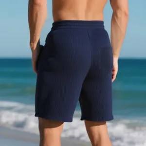 Back view detail of navy blue ribbed jacquard men's beach shorts on a sunny shore