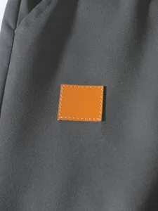Primo piano del tessuto twill grigio e della toppa in pelle arancione sui pantaloni cargo