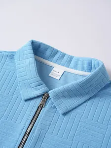 Close-up of light blue textured polo shirt showing zipper collar and material tag