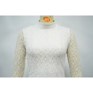 Dettaglio ravvicinato di un elegante body in pizzo floreale bianco con collo alto