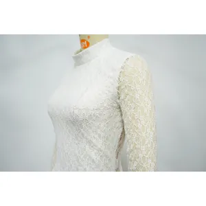 Dettaglio della trama in pizzo floreale bianco di alta qualità su un elegante body a maniche lunghe