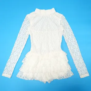 Dettaglio del pizzo floreale intricato e dell'orlo a balze a strati della tutina bianca.