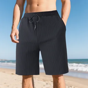Detail view of men's black jacquard beach shorts with drawstring waist on sunny beach