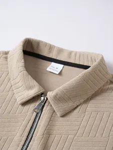 Macro view showing the intricate geometric texture and zipper detail of the beige polo shirt