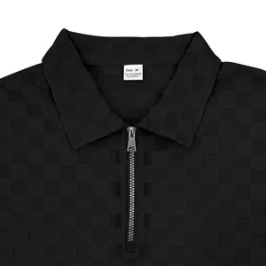 Detailed view of heavy black polo shirt featuring checkerboard jacquard fabric and half-zip
