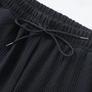 Close-up detail of black ribbed shorts featuring elastic waistband and drawstring tips