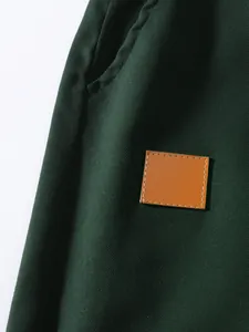 Vista ravvicinata del tessuto twill di cotone verde scuro con toppa in pelle marrone